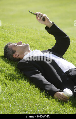 L'uomo, suit, telefono cellulare, tazza da caffè, prato, giacciono, take it easy, Foto Stock