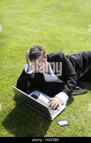 L'uomo, suit, portatile, telefono cellulare, prato, giacciono, take it easy, Foto Stock