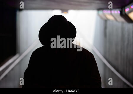 Silhouette di uomo in trilby e soprabito, in un sottopassaggio di Londra, Regno Unito Foto Stock