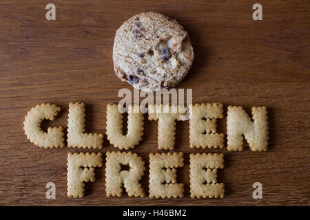 Il cibo consigli "senza glutine" scritto con alfabeto cookie sagomato a fianco di una pila di chip di cioccolato biscotti in legno. Foto Stock