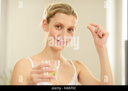 Giovane donna un bicchiere d'acqua, una compressa, Foto Stock