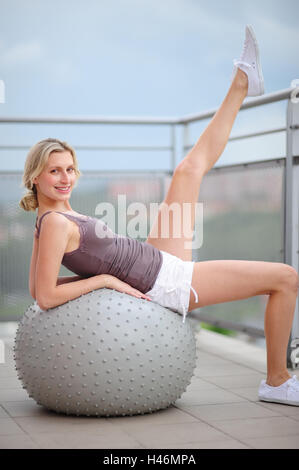 Giovane donna rende pratica di ginnastica con una palla di ginnastica, Foto Stock