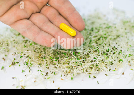 Una dose di sano di germogli alfalfa e una capsula di vitamina a mano. Foto Stock