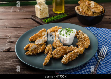 Le strisce di pollo nel pangrattato popcorn, con deliziosi aglio dip panini e toast Foto Stock