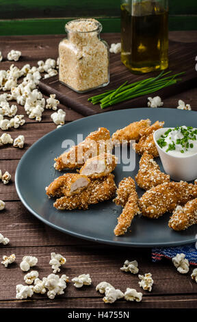 Le strisce di pollo nel pangrattato popcorn, con deliziosi aglio dip panini e toast Foto Stock