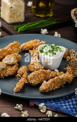 Le strisce di pollo nel pangrattato popcorn, con deliziosi aglio dip panini e toast Foto Stock