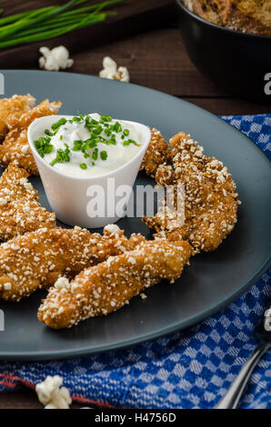 Le strisce di pollo nel pangrattato popcorn, con deliziosi aglio dip panini e toast Foto Stock