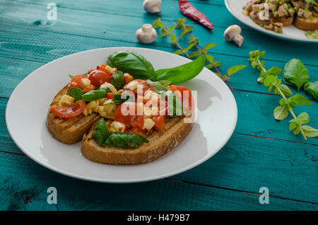 La bruschetta 2 tipi - classic con pomodoro, basilico e mozzarella, secondo tipo con funghi, il peperoncino e le erbe aromatiche Foto Stock