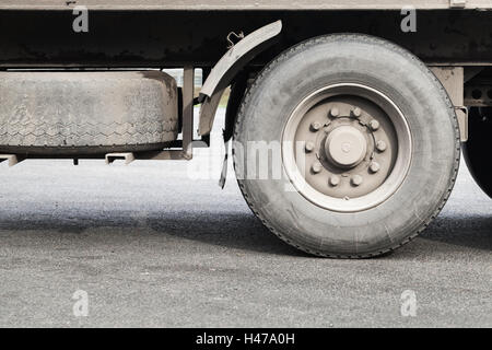 Le ruote sporche di camion su GRIGIO ASFALTO Foto Stock