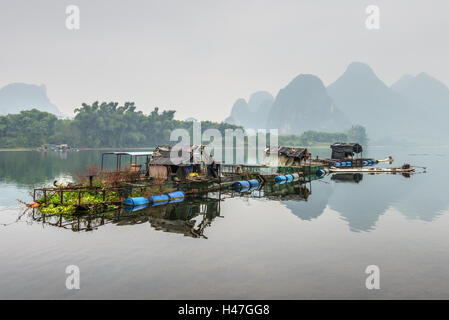 Case e zattera di bambù sul fiume Li isola galleggiante nella cortina di nubi brutto giorno nelle zone rurali Ya Foto Stock
