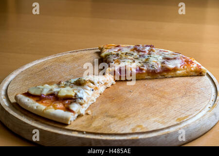 Avanzi di pizza pezzi su un tagliere di legno Foto Stock