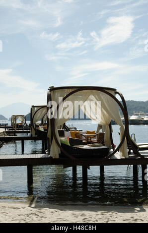 Spiaggia scena con padiglioni e barche in background Foto Stock