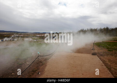 La gente a piedi attraverso il vapore a sito di Geysir Islanda Foto Stock