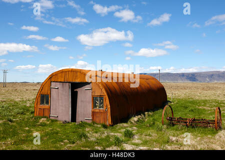 Vecchia ruggine nissen hut su terreno coltivato in Islanda Foto Stock