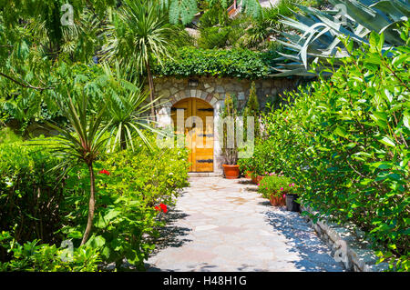 Il lussureggiante giardino paesaggistico di fronte la piccola casa, che si preannuncia come l'entrata alla fiaba, Rezevici, Montenegro. Foto Stock