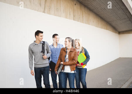 Gruppo, uomini, donne, conversazione, adulti, studenti, quattro, mantenuti scolaro, tirocinanti, felice, ridere, cartelle di lavoro le cartelle Foto Stock