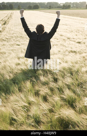 Giovani manager sta in un campo, gioia, tifo, vista posteriore, Foto Stock