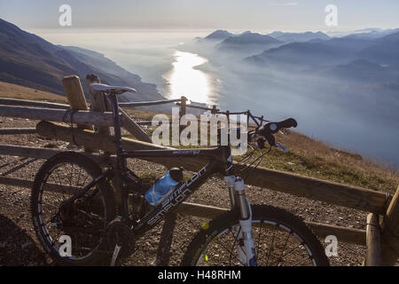 Mountain bike appoggiata contro la recinzione di legno, vista dal Monte Baldo sul Lago di Garda , Foto Stock