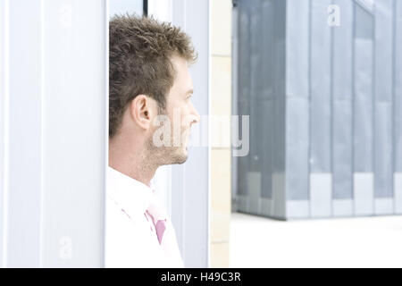 Edifici, uomo, giovani, seriamente visualizza distanza, pagina ritratto, azienda Building, edificio di uffici, business, stand, Vista, Vista, persona, imprenditore, barba di tre giorni, barba lunga, interrogatorily, premuroso, incredula, indeciso, con lungimiranza, lungimiranza, esterno, Foto Stock