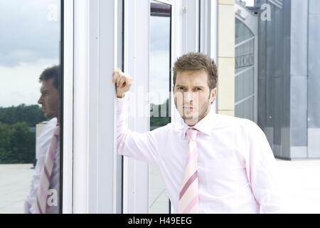 Edifici, uomo, giovani, seriamente, magro, di mezza ritratto, azienda Building, edificio di uffici, business, stand, facciata, persona, imprenditore, barba di tre giorni, barba lunga, dapperly, elegantemente, smart, stand, interrogatorily, premuroso, incredula, self-fiduciosamente, risolutamente, orientati al successo futuro, esterno, Foto Stock