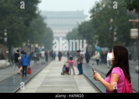 Pechino, Cina. Xiv oct, 2016. Una donna che indossa la maschera passeggiate su smog avvolta Qianmen Street a Pechino Capitale della Cina, il 14 ottobre 2016. Credito: Ju Huanzong/Xinhua/Alamy Live News Foto Stock