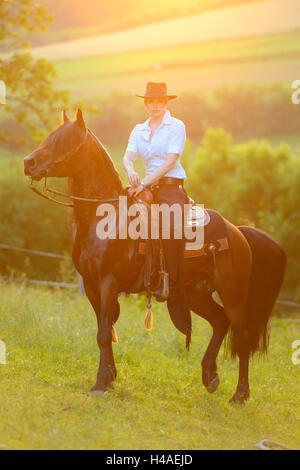 Giovane donna, pony Connemara, stallone, cinghia, vista laterale, ride, guardando la telecamera, Foto Stock