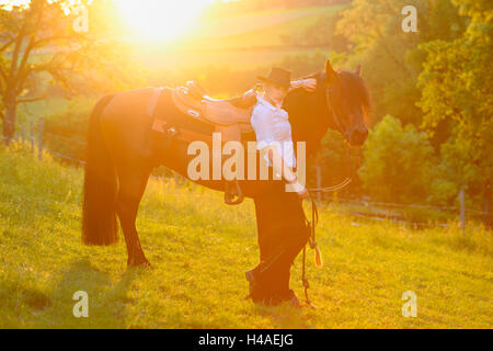 Giovane donna, pony Connemara, stallone, cinghia, vista laterale in piedi, guardando la telecamera, Foto Stock