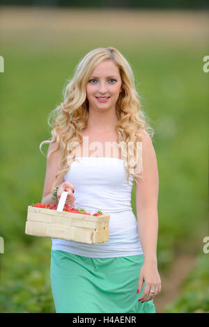 Giovane donna su un campo di fragole, Foto Stock