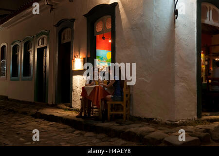 Gli amici di notte davanti a una strada con bar Foto Stock