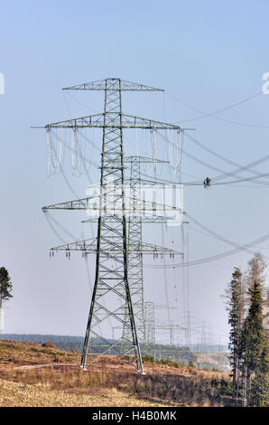 Alta tensione pali, fili, uomo che lavora sulla linea di potenza di installazione, gondola, legno, swath, Foresta Turingia Foto Stock