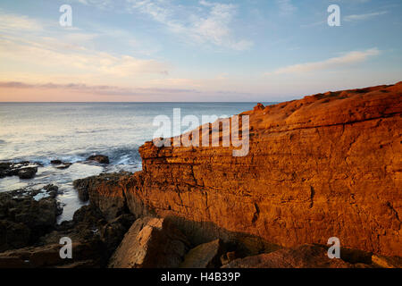 Sunrise oltre la costa di roccia in Atlantico a Luz, a ovest di Lagos, Algarve, Portogallo, Europa Foto Stock