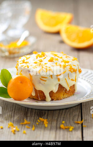 Piccola torta arancione con glassa bianca sulla piastra Foto Stock