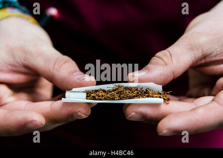 Le mani la laminazione di una sigaretta con il tabacco e il filtro, fumatori Foto Stock