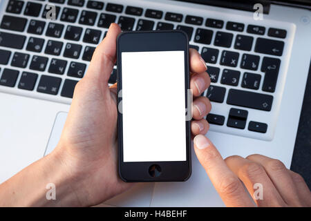 Donna mani dello smartphone mostrando la schermata bianca con la tastiera portatile in background Foto Stock