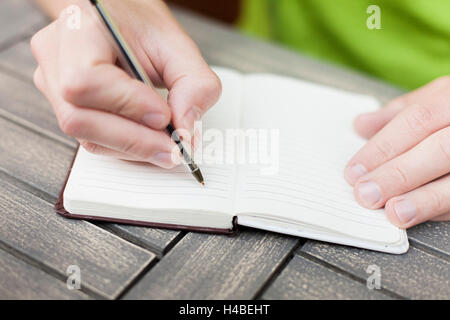 Giovane uomo scrivere appunti su un notebook con una penna, una veduta ravvicinata delle mani Foto Stock
