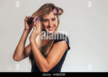 Donna mettendo in arricciare i capelli Foto Stock