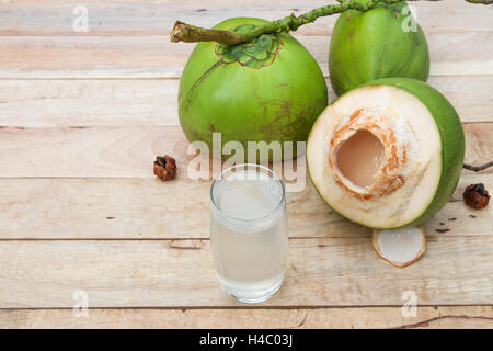 Cocco fresco da bere acqua in bottiglie di vetro con foglia di cocco su sfondo di legno Foto Stock