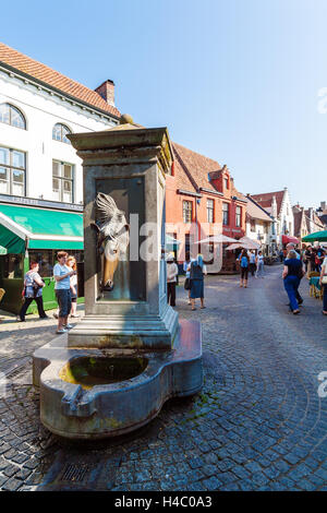 BRUGES, Belgio - Aprile 6, 2008: i turisti a camminare per le strade della città vecchia vicino alla fontana con testa di cavallo Foto Stock