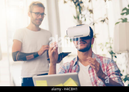 Gli imprenditori test di realtà virtuale tecnologia con un collega in ufficio. Foto Stock