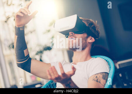 Stupito uomo guardando in un VR occhiali e gesti Foto Stock
