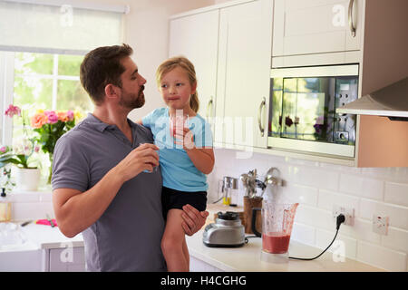 Padre e figlia godendo in casa frullati in cucina Foto Stock