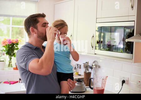 Padre e figlia godendo in casa frullati in cucina Foto Stock