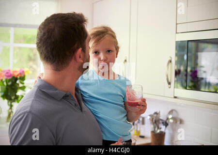 Padre e figlia godendo in casa frullati in cucina Foto Stock