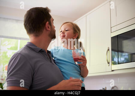 Padre e figlia godendo in casa frullati in cucina Foto Stock