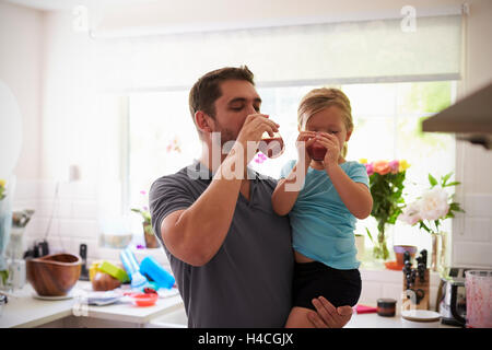 Padre e figlia godendo in casa frullati in cucina Foto Stock