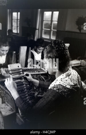 Eine Zigarrenrollerin in Marburger Tracht bei der Arbeit in einer Zigarrenfabrik bei Marburg, Deutschland 1930er Jahre. Una femmina di sigaro a rulli che indossa un abito di Marburg / costume di lavorare in un tessuto di sigaro vicino a Marburg, Germania 1930 Foto Stock