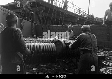 Lagerarbeiter der Rhenania Ossag Mineralölwerke AG DI AMBURGO das verladen Bitumenprodukt Mexphalt auf Schiffe, Deutschland 1930er Jahre. Warehousemen della Rhenania Ossag Mineraloelwerke AG ad Amburgo il carico di una nave con il bitume prodotto Mexphalt, Ge Foto Stock