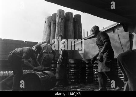 Lagerarbeiter der Rhenania Ossag Mineralölwerke AG DI AMBURGO das verladen Bitumenprodukt Mexphalt auf Schiffe, Deutschland 1930er Jahre. Warehousemen della Rhenania Ossag Mineraloelwerke AG ad Amburgo il carico di una nave con il bitume prodotto Mexphalt, Ge Foto Stock