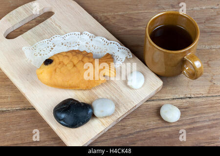 Taiyaki, giapponese a forma di pesce pancake. Mangiare con il tè caldo sulla tavola di legno Foto Stock