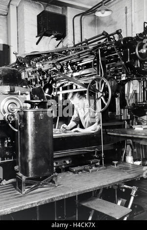 Ein Arbeiter justiert die Rotationsdruckmaschine in den Werken des Maschinenbaukonzerns MAN (Maschinenfabrik Augsburg-Nürnberg), Deutschland 1930er Jahre. Un lavoratore regolare la stampa rotativa premere negli impianti di ingegneria meccanica azienda MAN Foto Stock